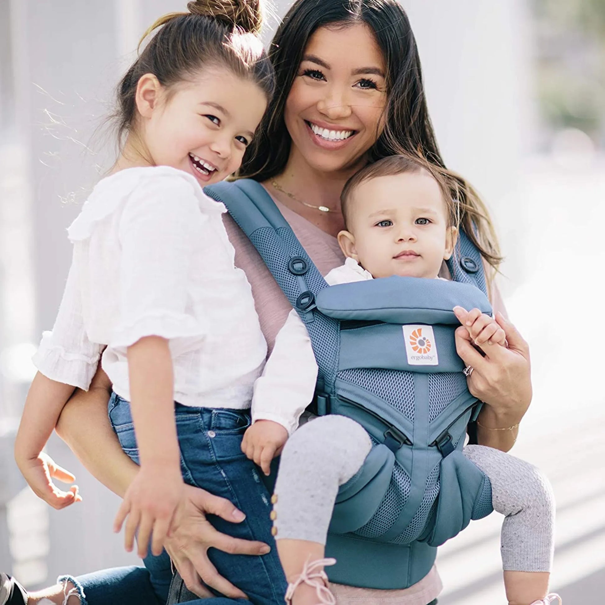 Mãe usando canguru ergonômico Ergobaby com bebê de frente em posição segura